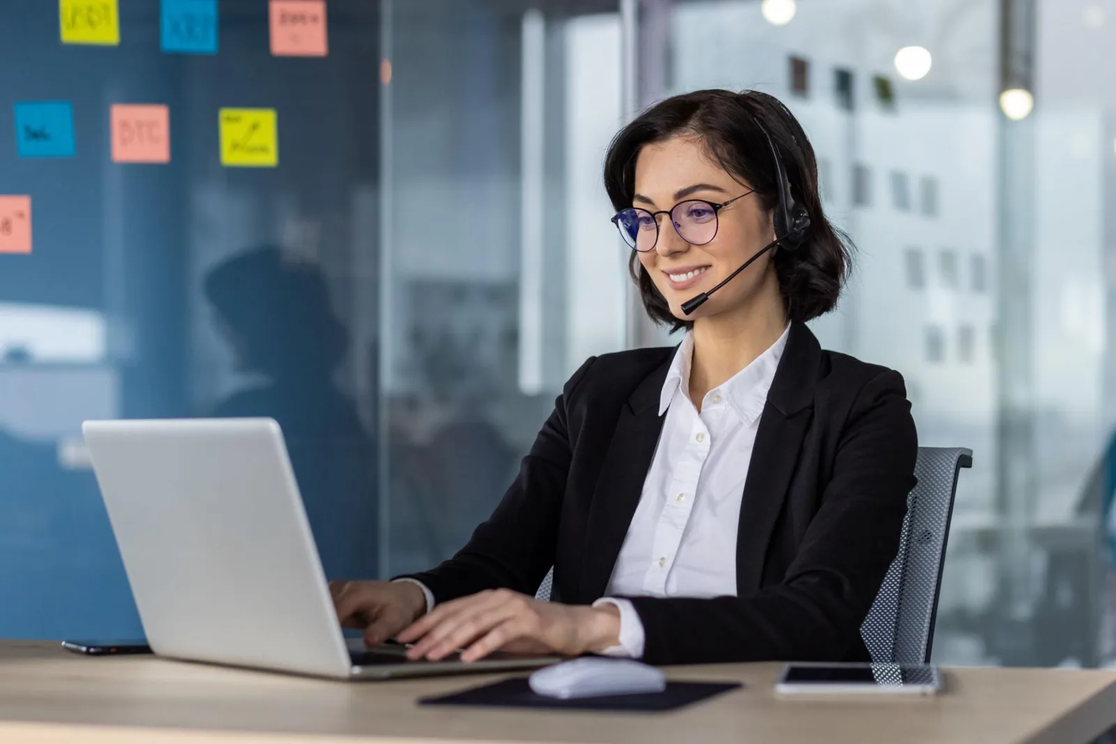 Customer support representative assisting a client by phone at a desk
